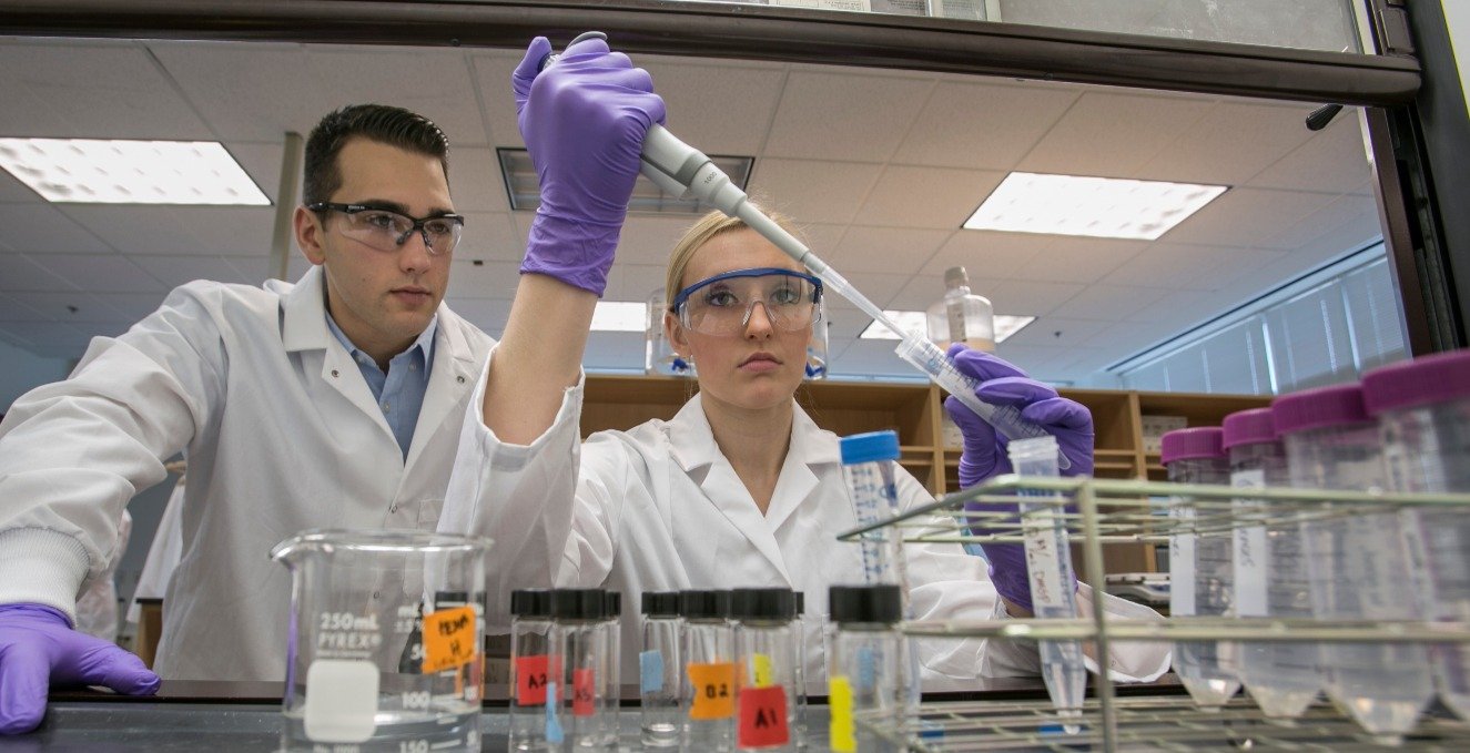 Two researchers using a syringe and test tube