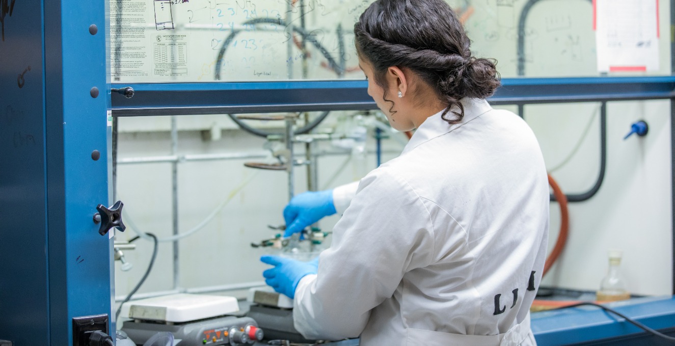 Researcher working behind protection shield