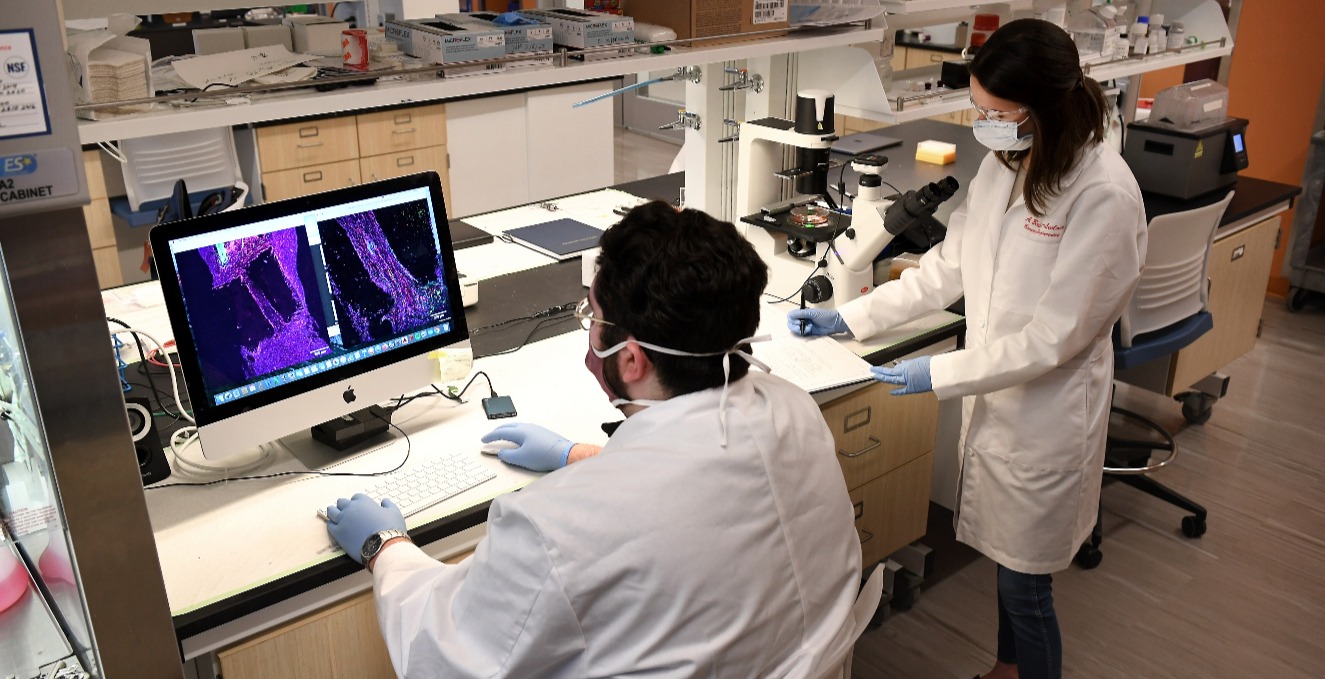 two researchers discuss research at a computer in a lab